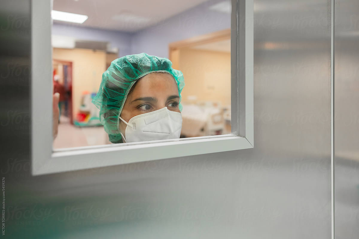 Nurse looking through window of operating room door