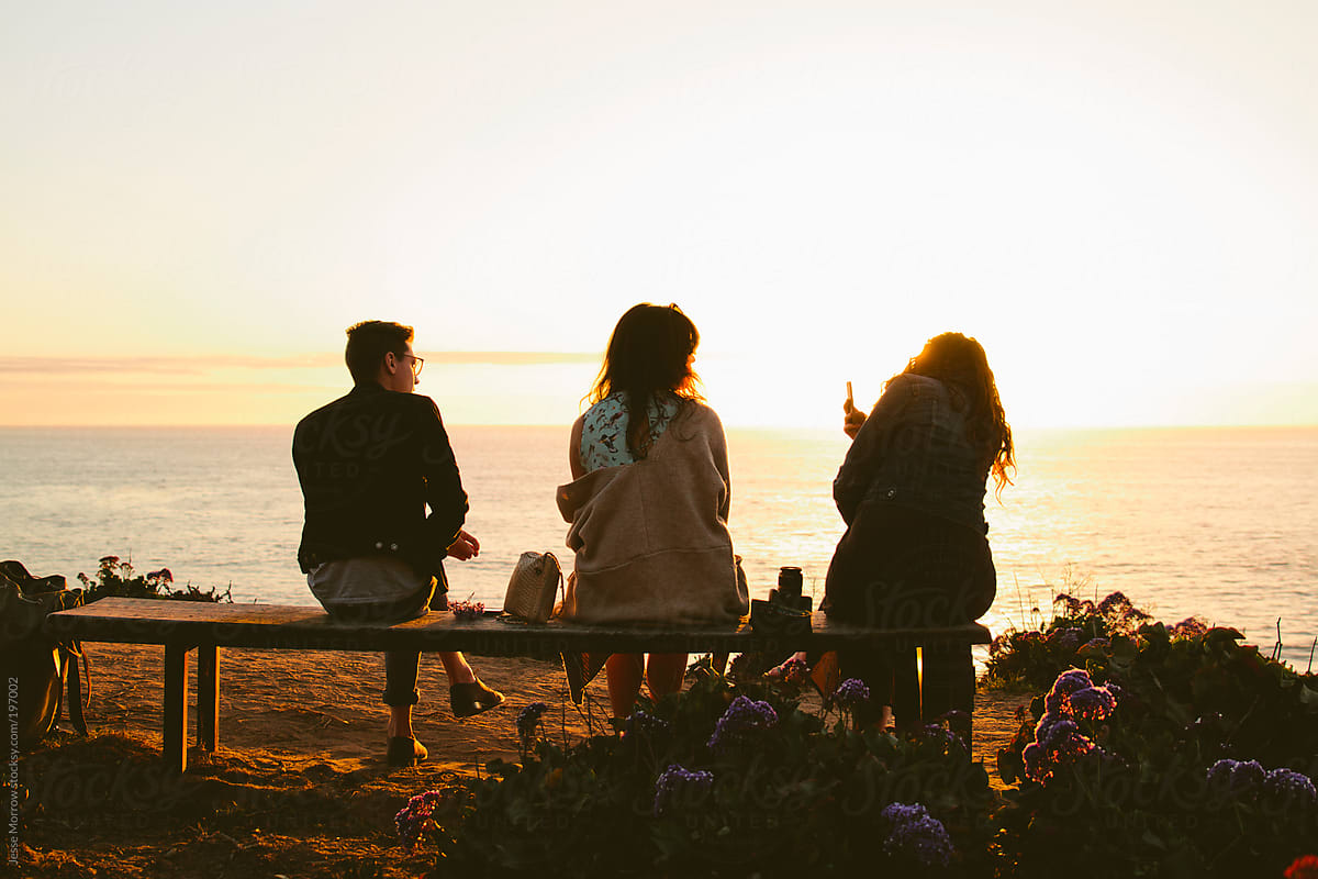 Group sits on bench watching sunset