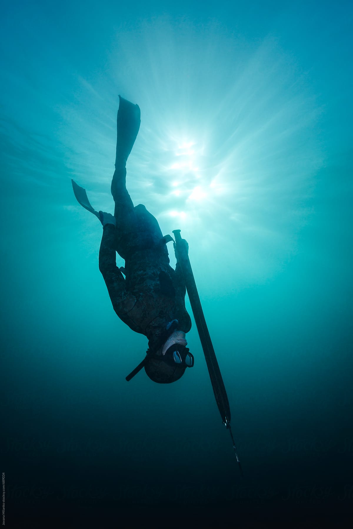 Spearfisherman diving in deep blue water of  Bali