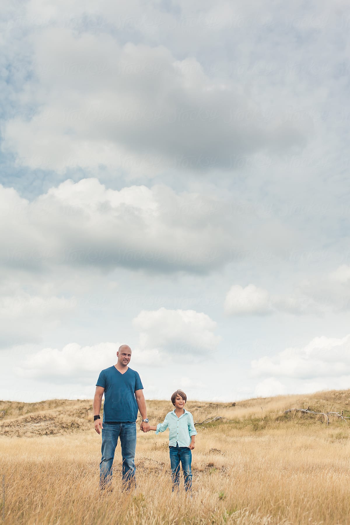 Father and son standing in a golden field against a big sky