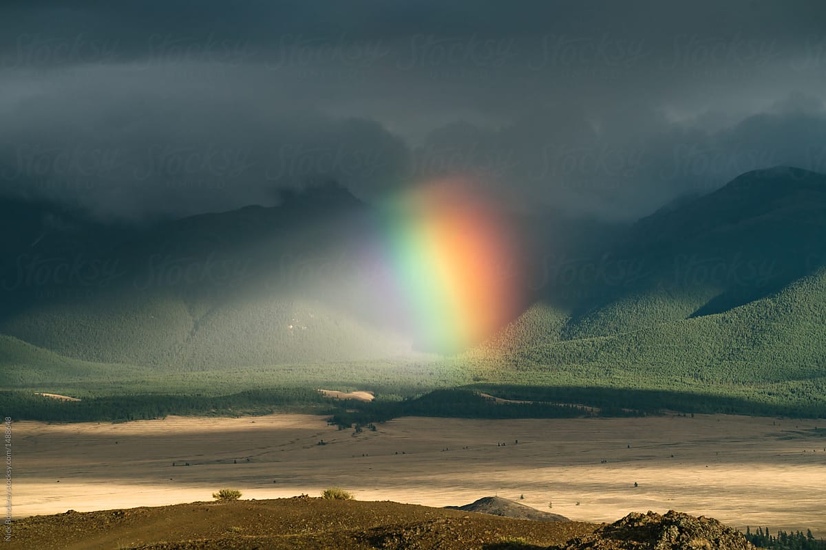 Rainbow over mountains in stormy weather