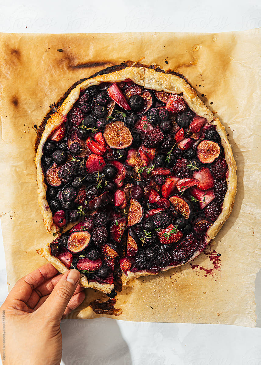 Hand holding piece of freshly baked berry galette