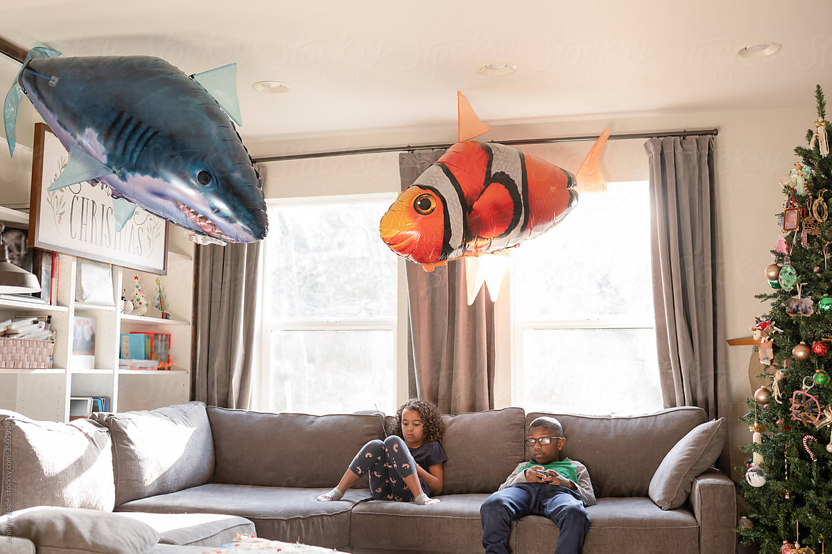 Siblings play with remote controlled balloon fish