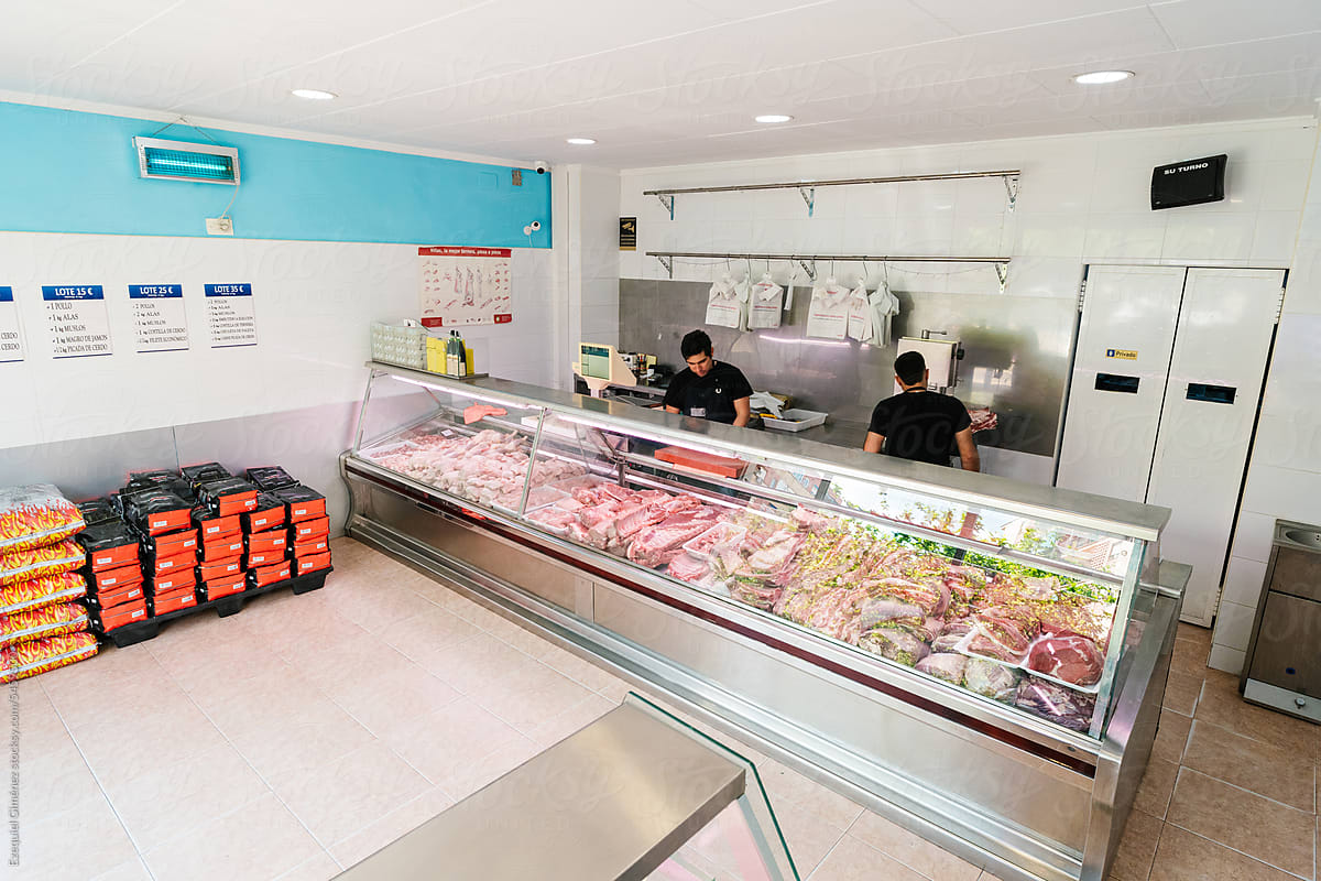 Workers at counter with meat in shop