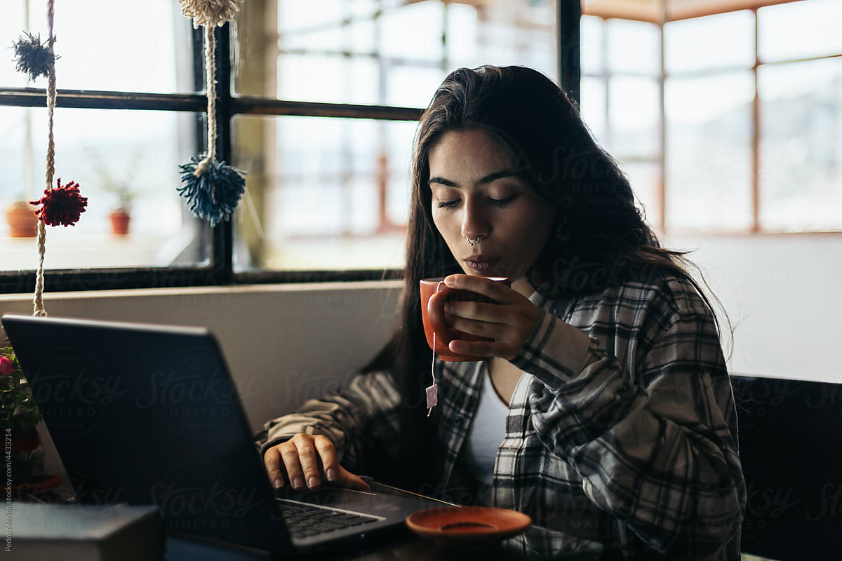 Freelance woman working with laptop in cozy workplace