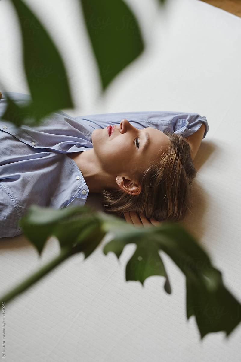 Portrait Of A Woman Lying On A Bed Through Monstera Leaves Del Colaborador De Stocksy Amor