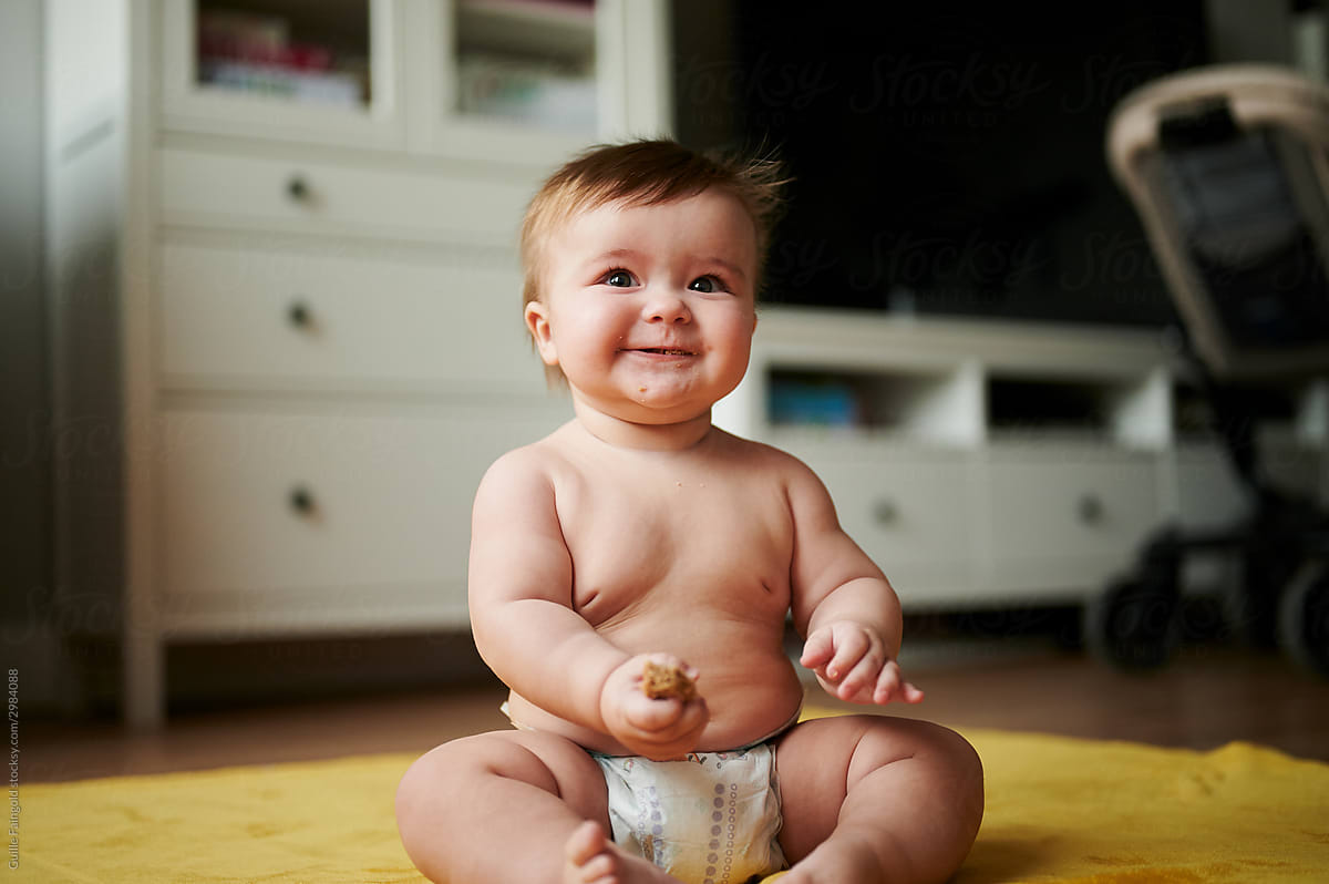 Happy baby enjoying snack on floor