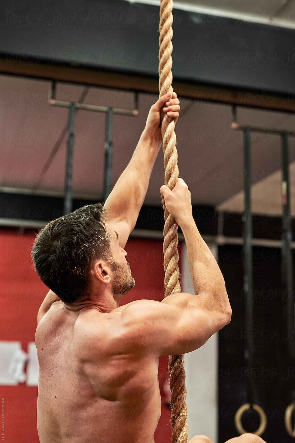 Strong athlete on rope in a gym
