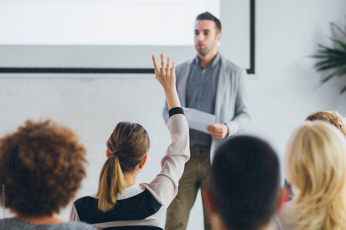 Woman Holding Her Hand Up to Ask a Question to a Lecturer.