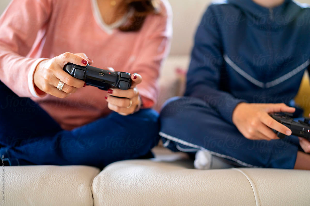 Faceless mother and son playing videogame on couch