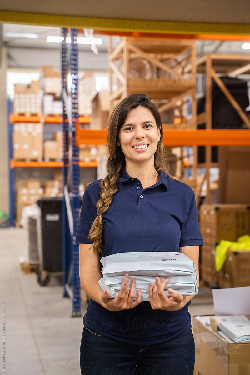 Smiling Woman Holding Parcels At Warehouse
