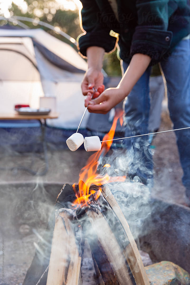 Young adult in outdoor camp setting with marshmallows.