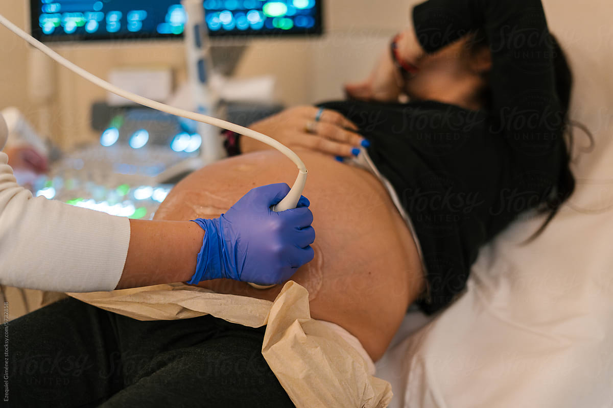 Faceless pregnant woman and scanning doctor hand in lab