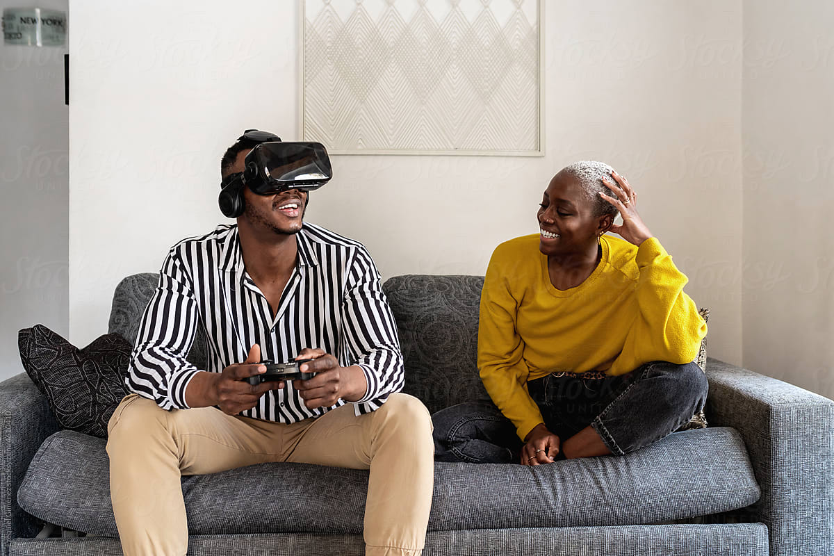 Black female watching boyfriend playing VR videogame