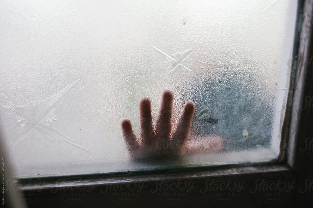 Toddler\'s finger behind a glass window pane