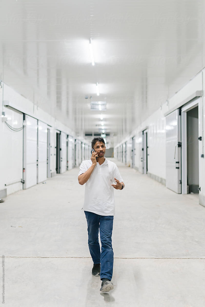 Man speaking on smartphone in warehouse corridor