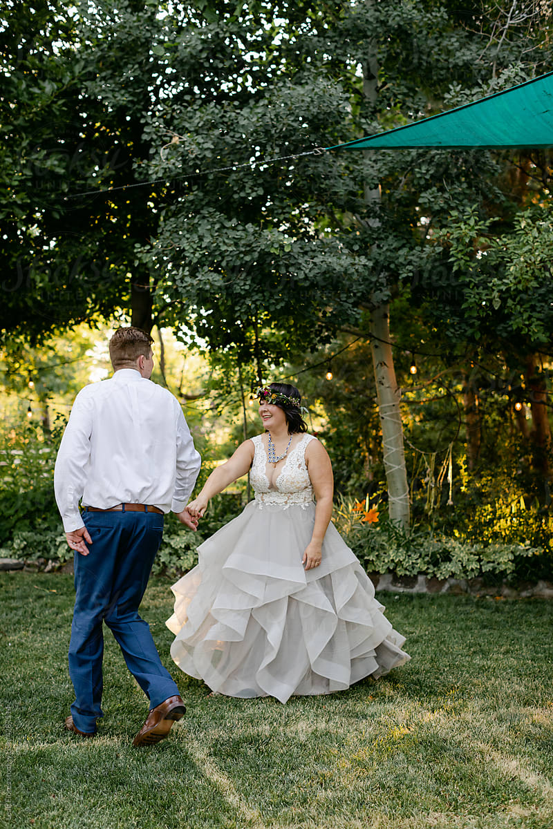 A Smiling Bride and Groom Hold Hands and Dance Together