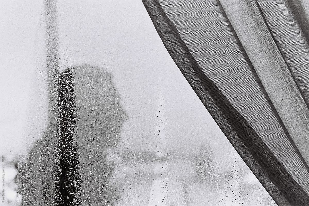 Silhouette of a man through a wet window, black and white