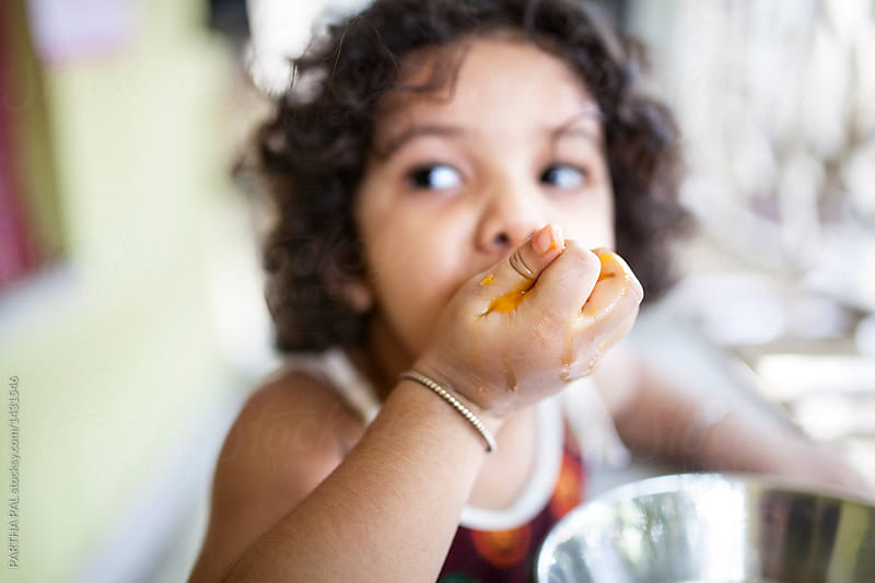 Kid enjoy eating mango with juicy hand