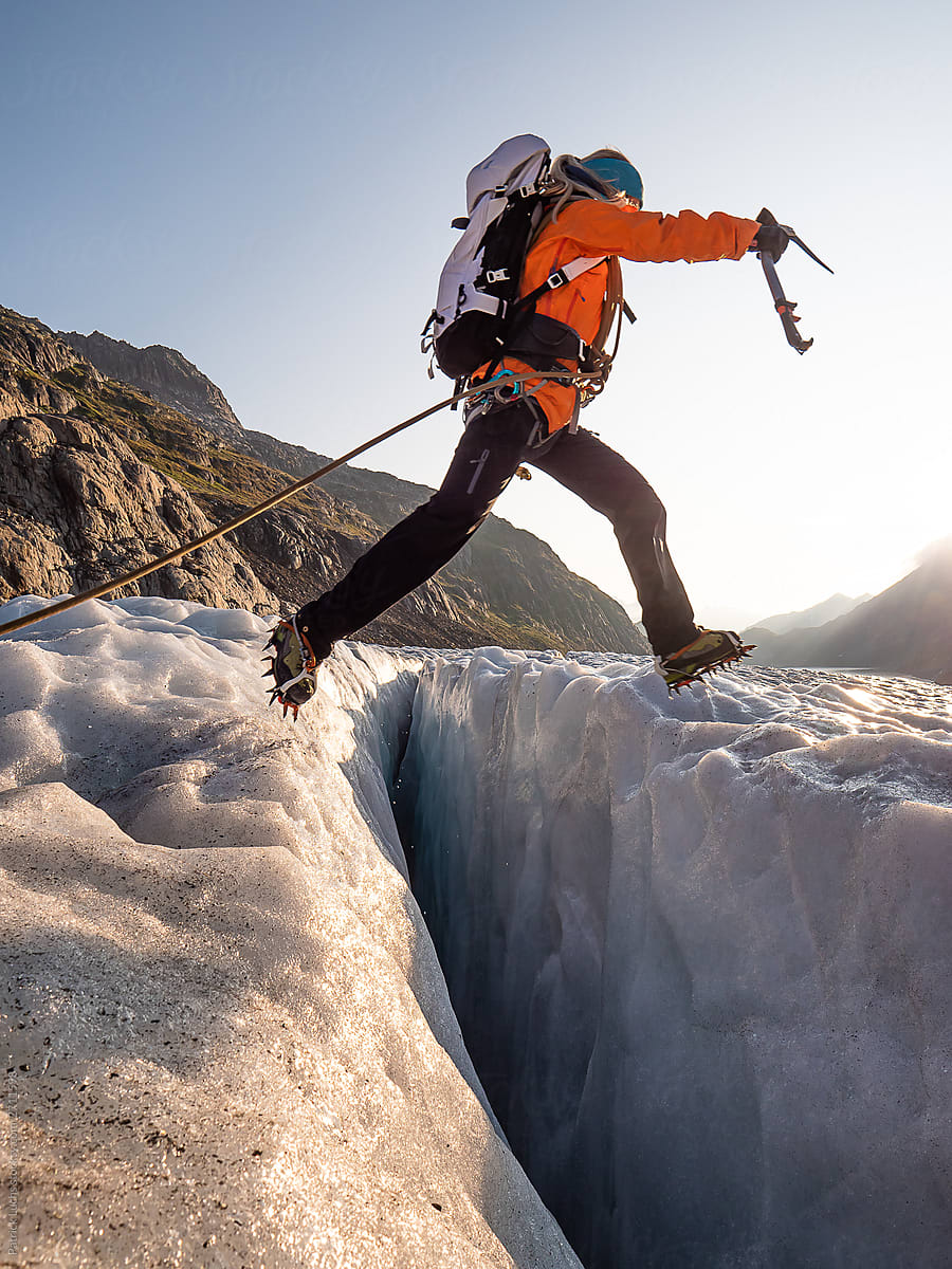 girl with ice axe jumping crevasse