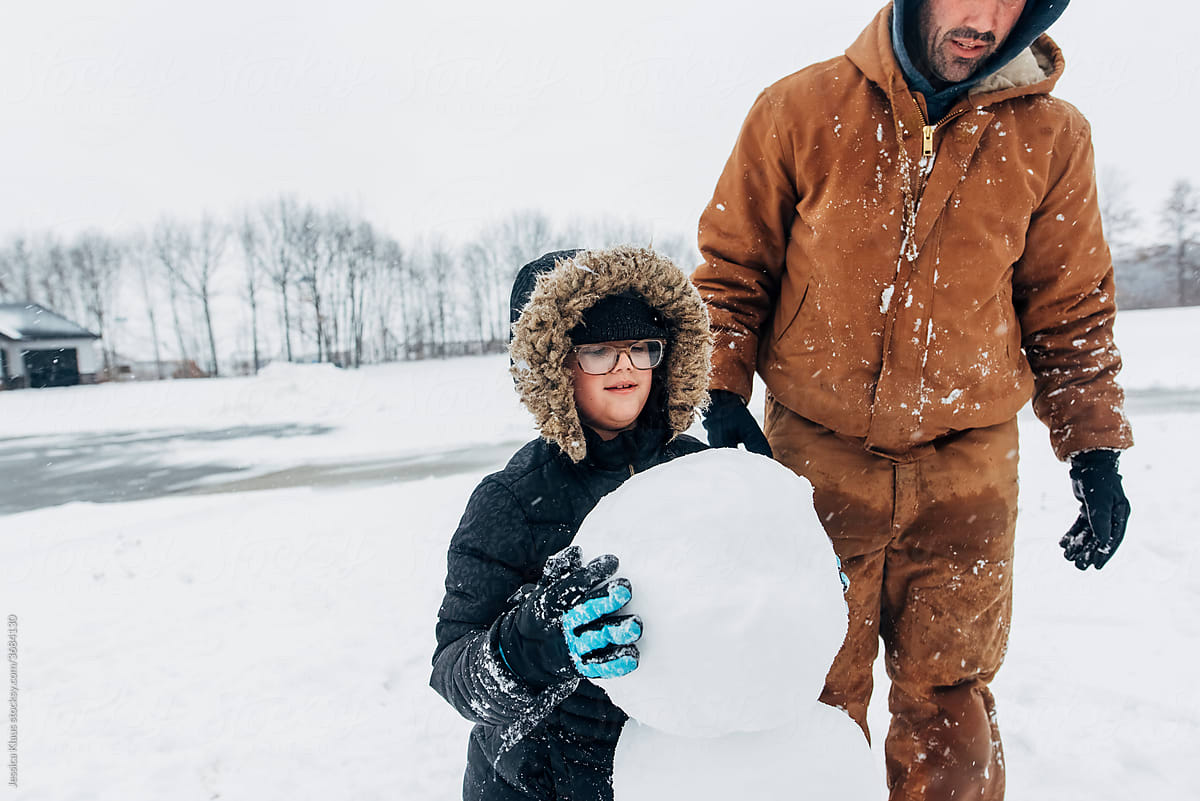 Girl placing snowball on top of snowman.