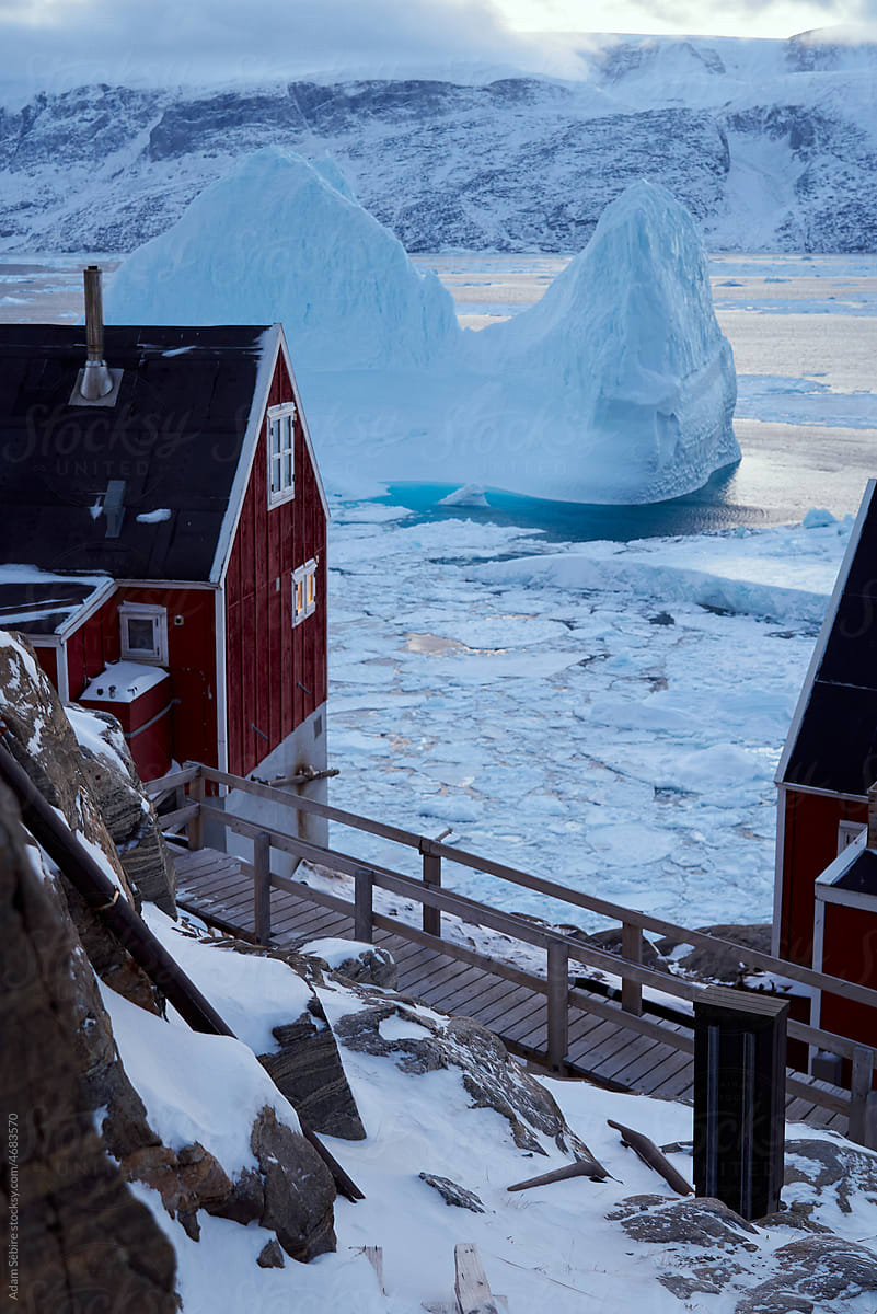 Huge glacier iceberg passes village houses in a Greenlandic town