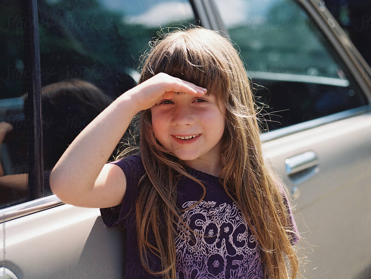 smiling girl standing outdoors by an old car in summer