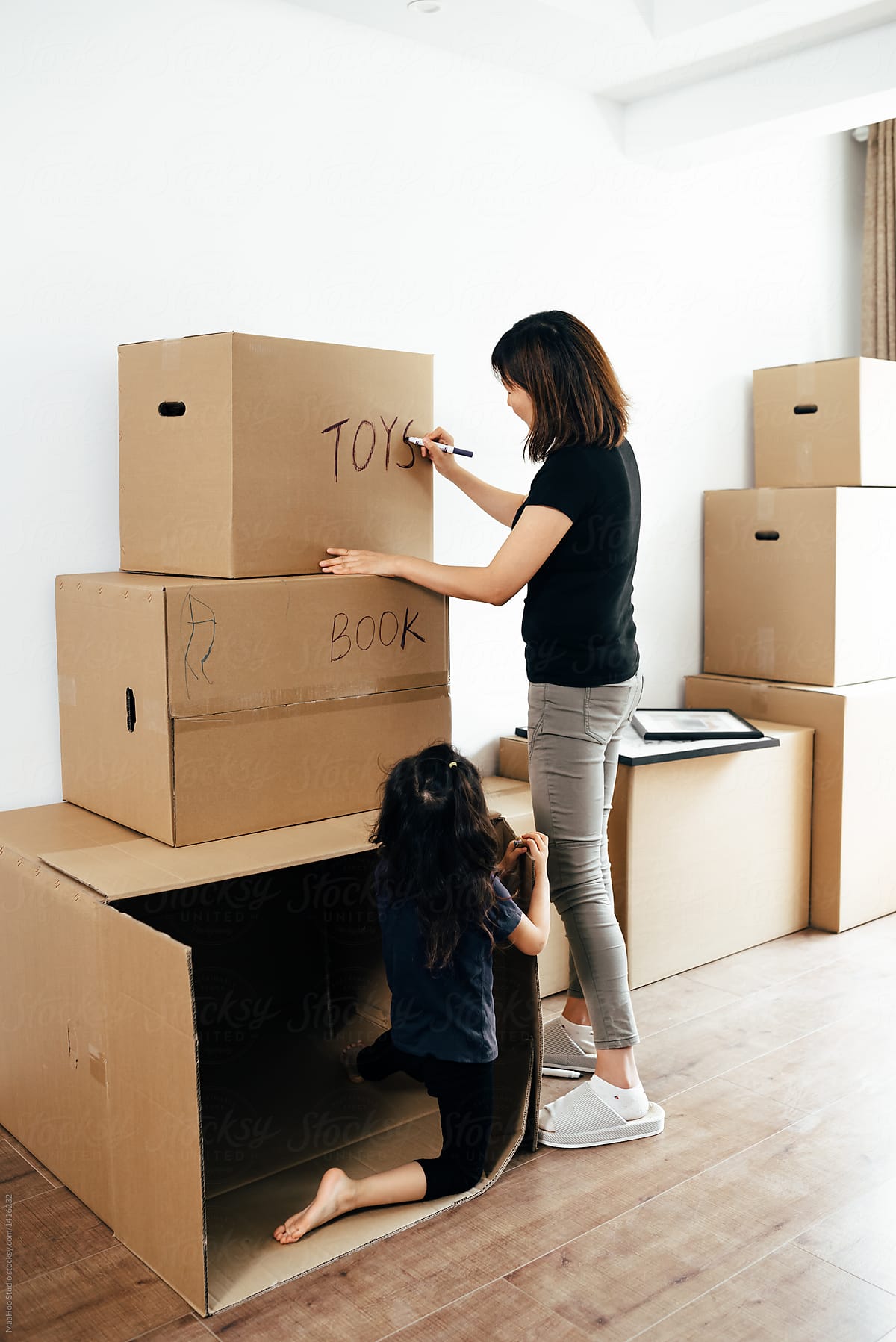 Young mother and her daughter moving boxes
