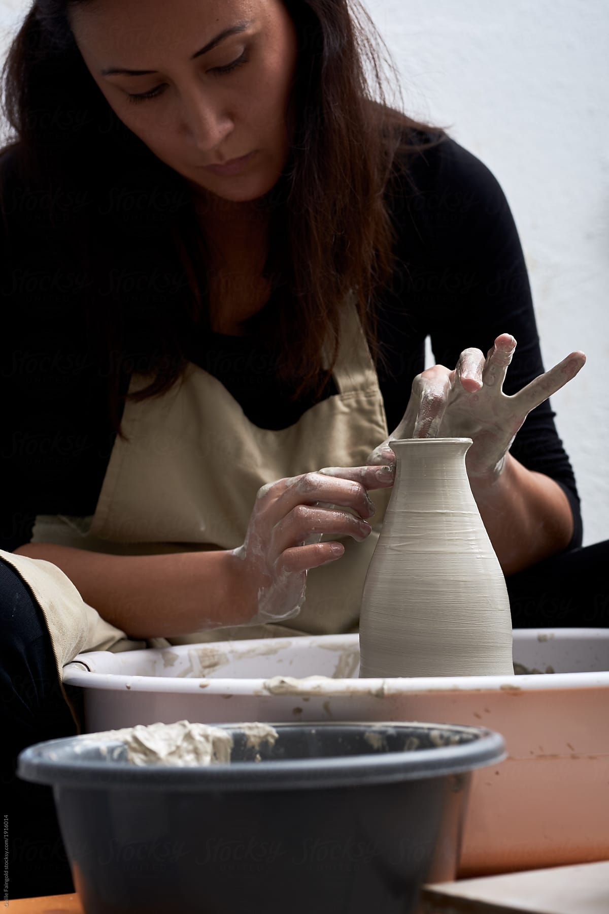 Woman working with clay vase in her studio.