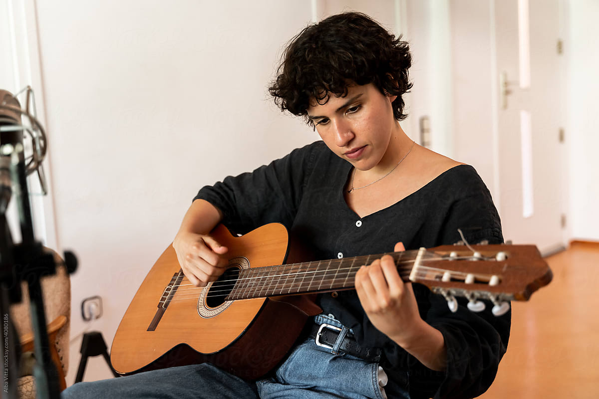 Serene young woman playing music at home studio
