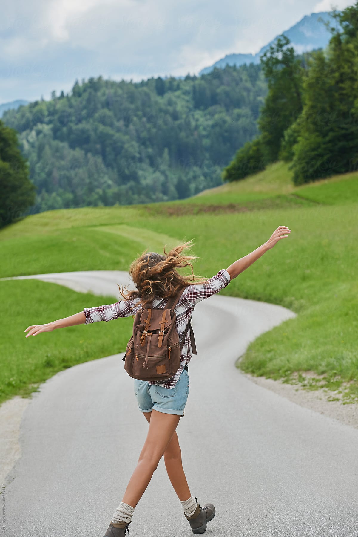 Happy girl dancing on scenic countryside road