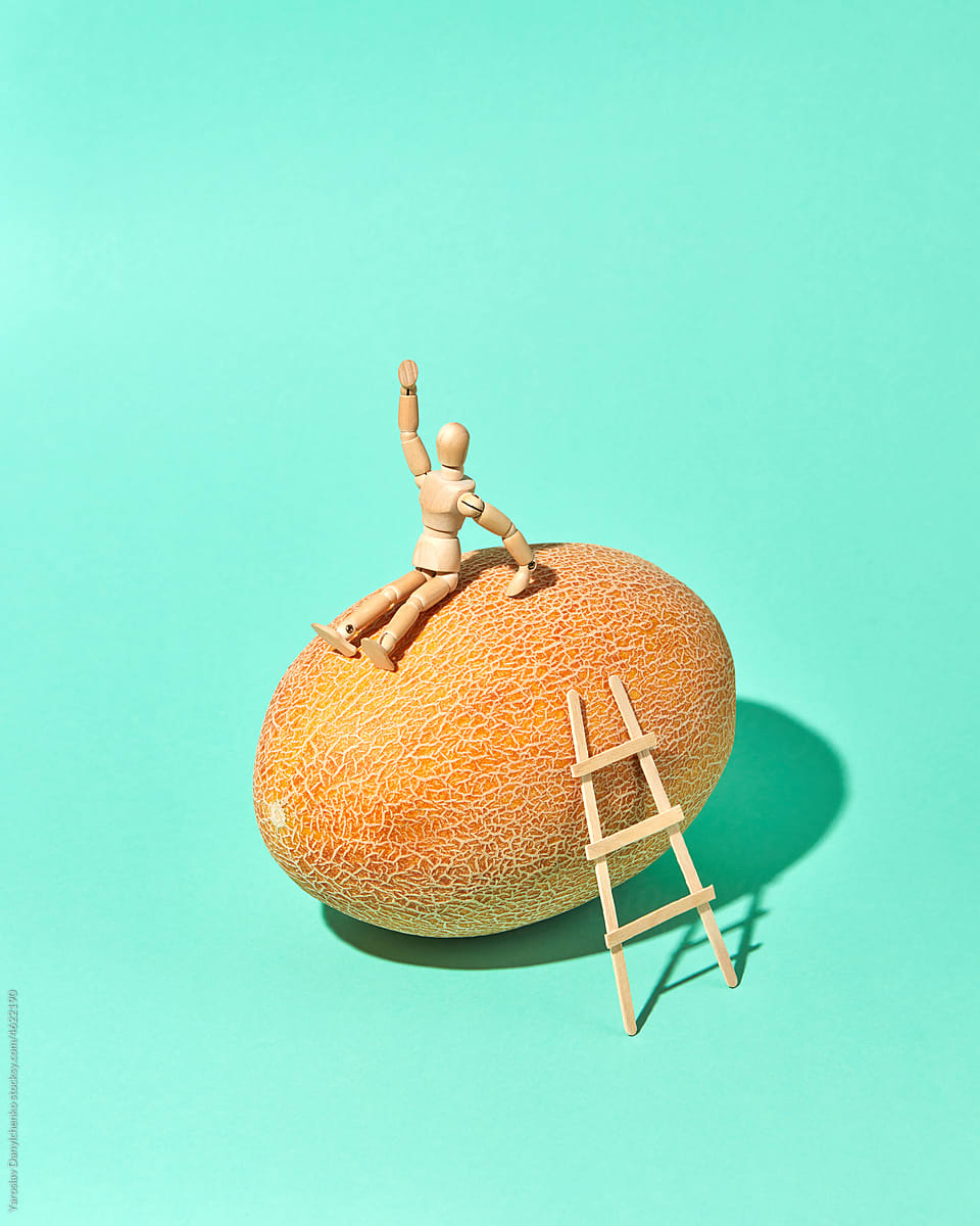 Movable human miniatures model sits on a fresh melon.