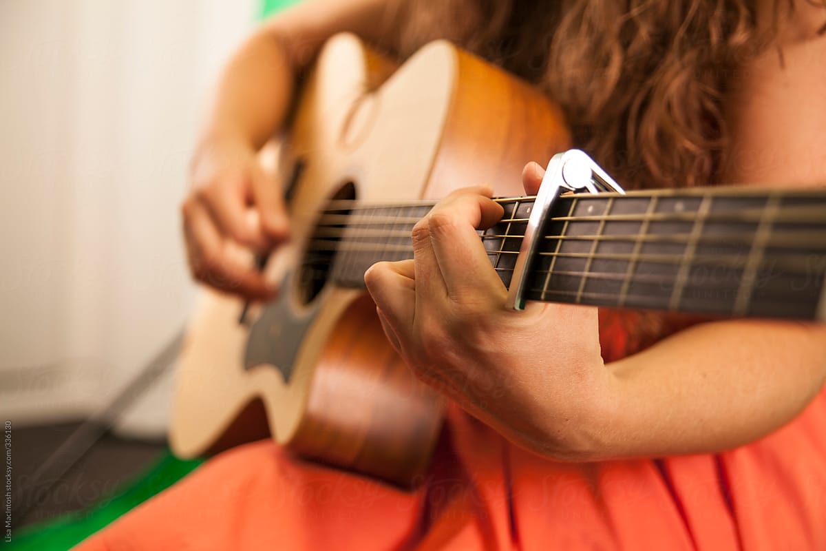 woman's hands strumming guitar