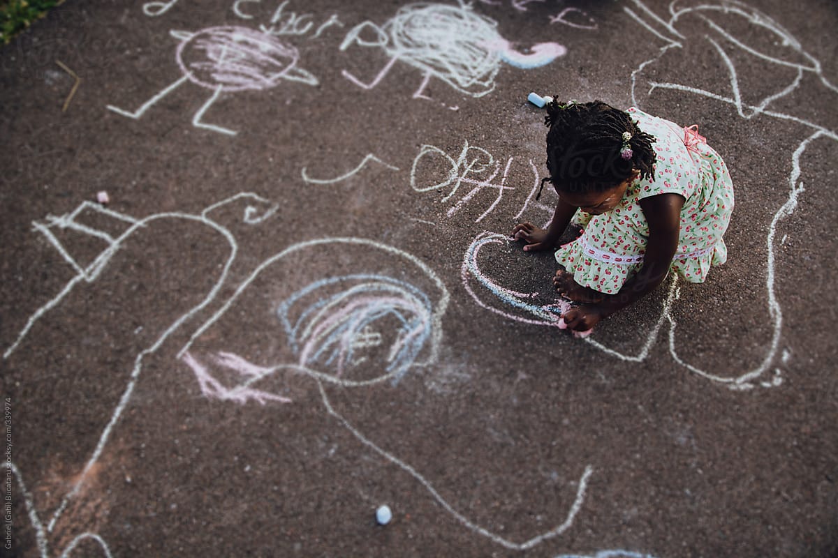 African-American Girl Drawing With Chalk on Driveway