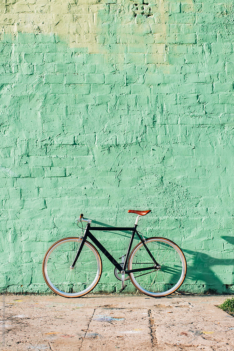 Minimalist Black Single-Speed Bicycle Against Green Brick Wall