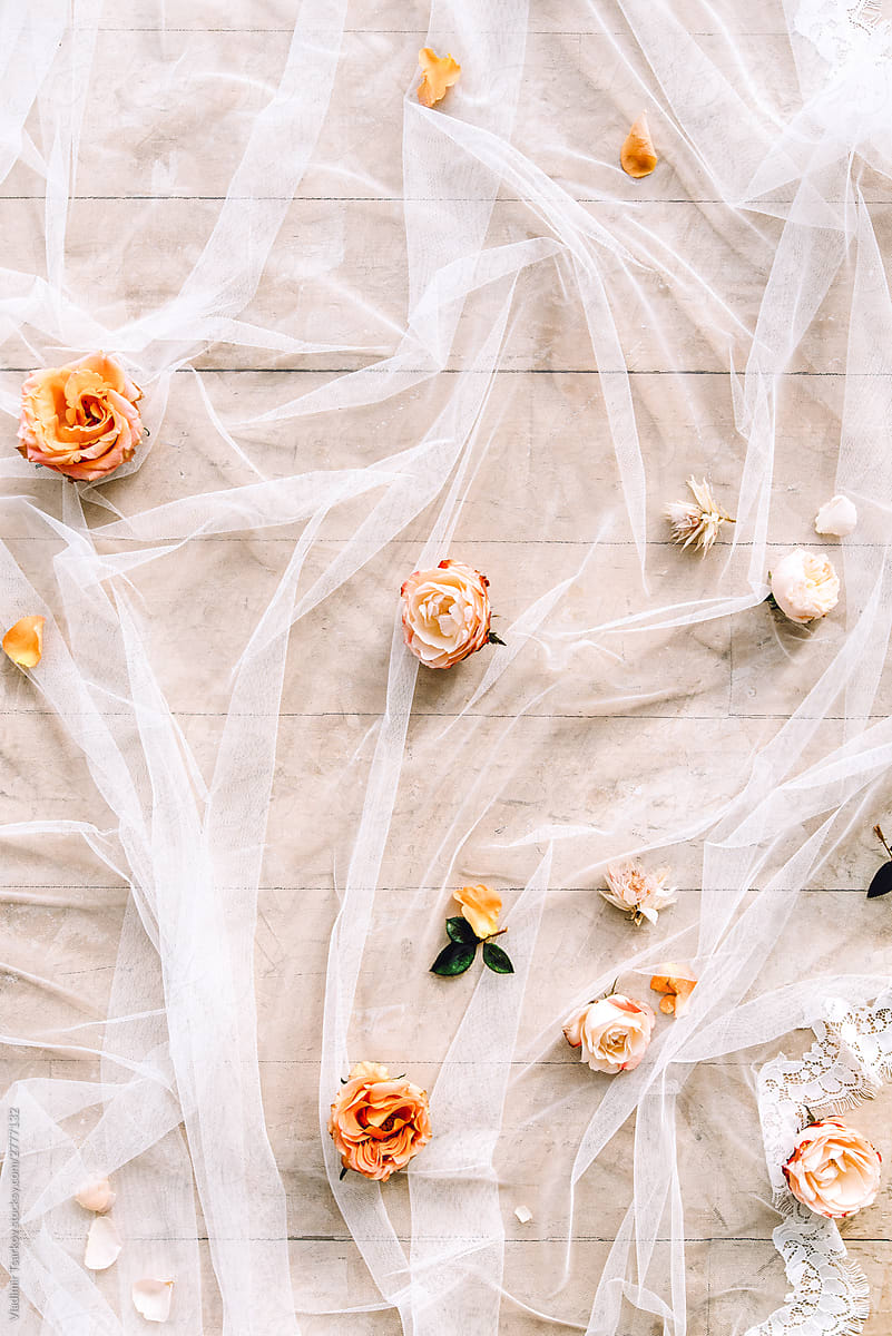 flat lay with roses and white chiffon fabric on wooden floor background