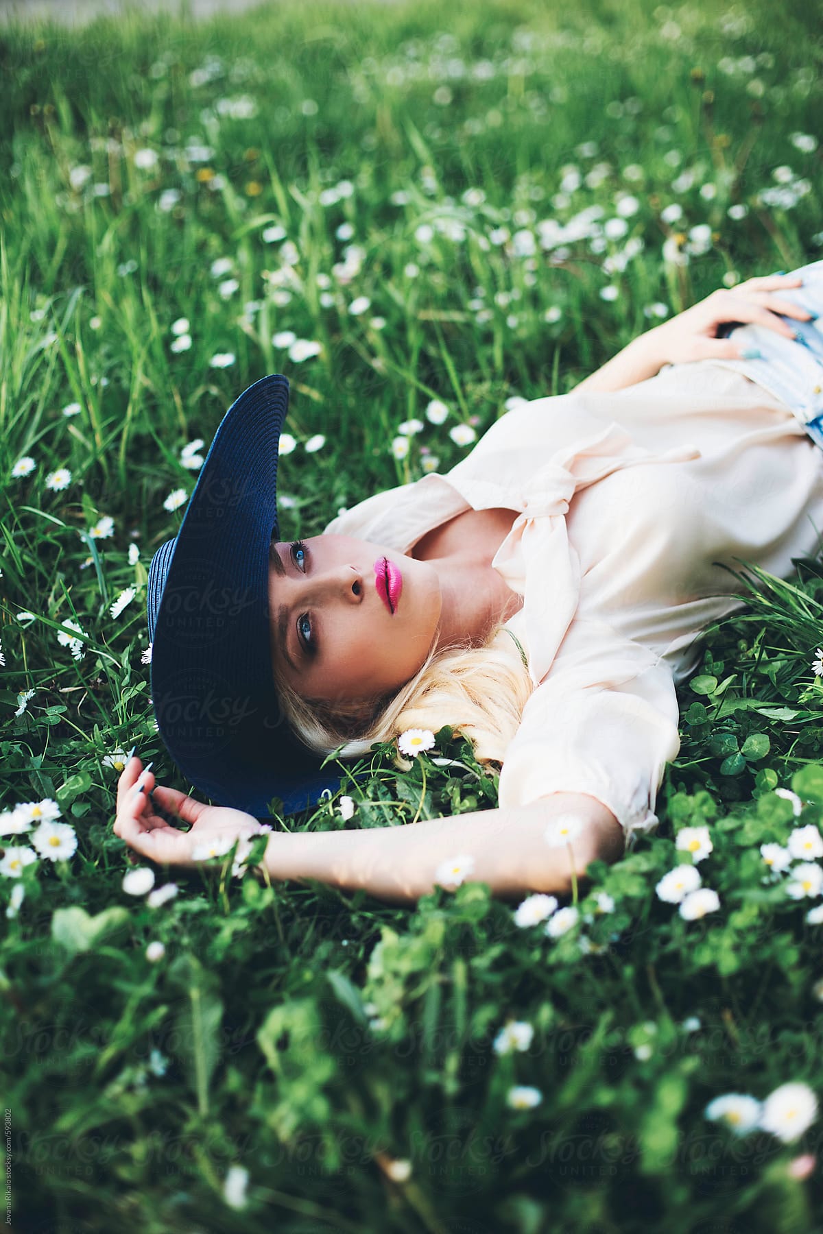 Beautiful Young Woman Lying On Grass Wearing A Summer Hat By Stocksy Contributor Jovana 