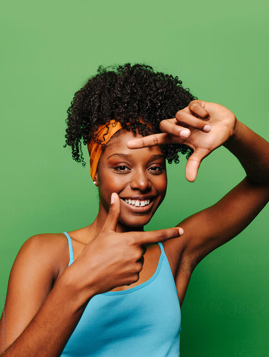 Cheerful black woman showing frame gesture