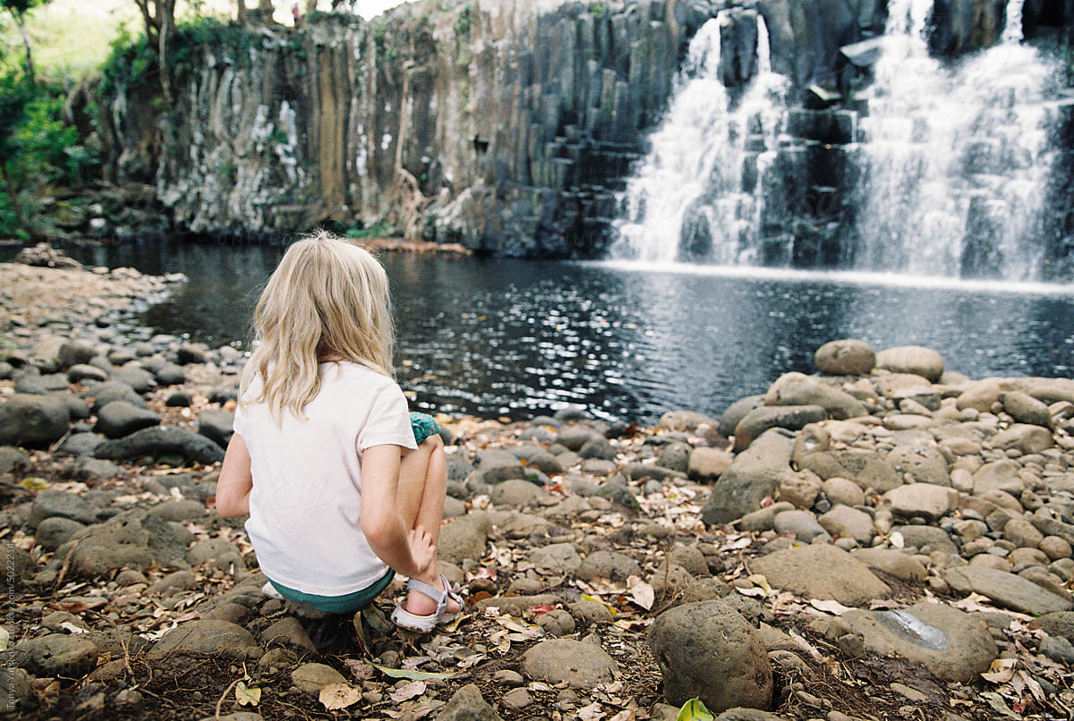 A girl sitting near the waterfall