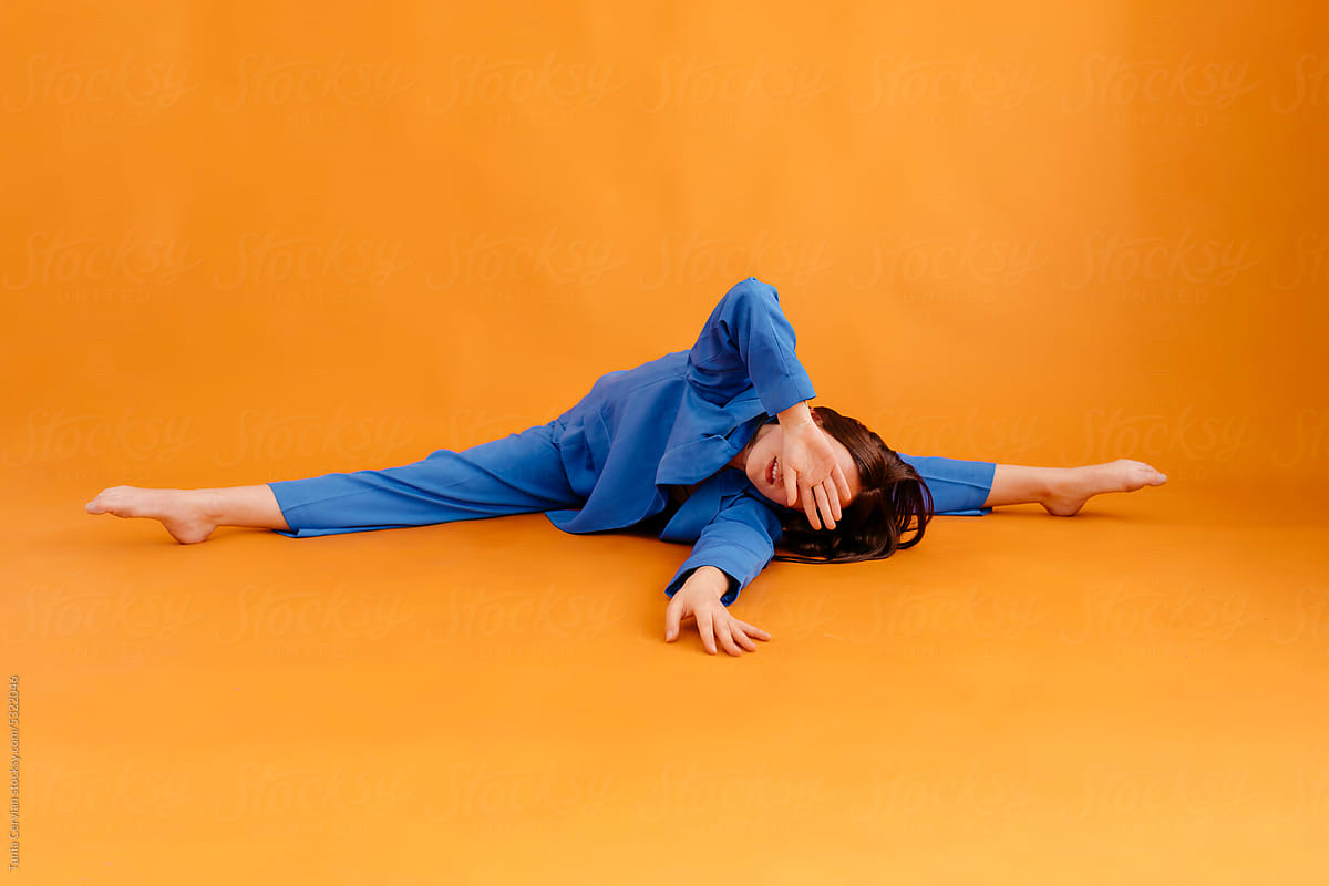 Flexible woman doing exercise on floor in orange room