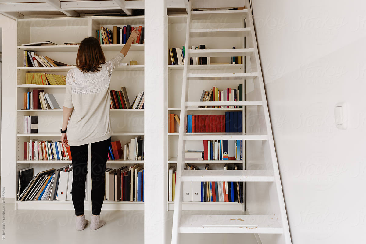  Woman Taking Books From Shelf By Stocksy Contributor Milles Studio 