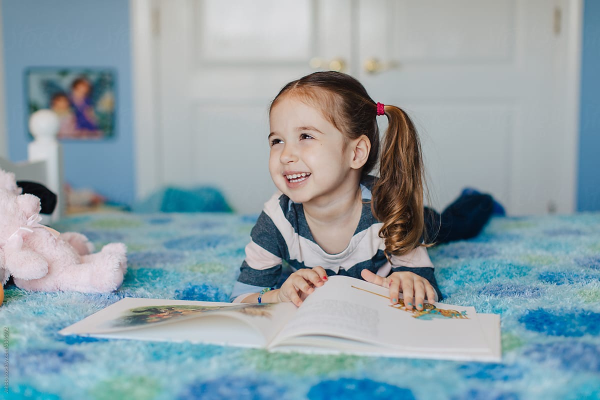Toddler laying on a bed reading a book