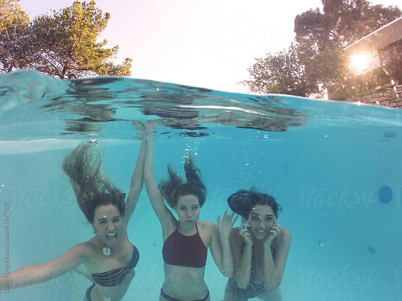Three friends having fun underwater in swimming pool