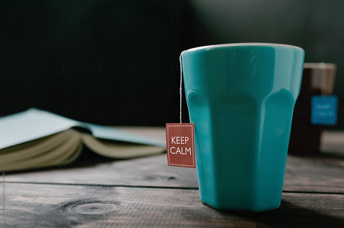 Mug, Tea Tag saying 'Keep Calm'  and an Open Book on a Wooden Table