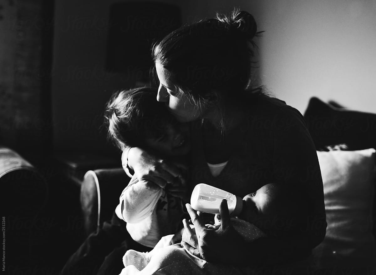 black and white photo of mom kissing child at home