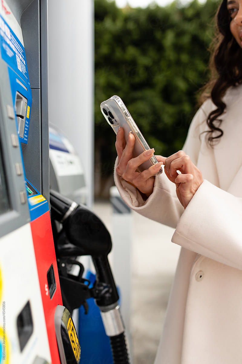 Young Woman Uses A Mobile App At The Gas Station