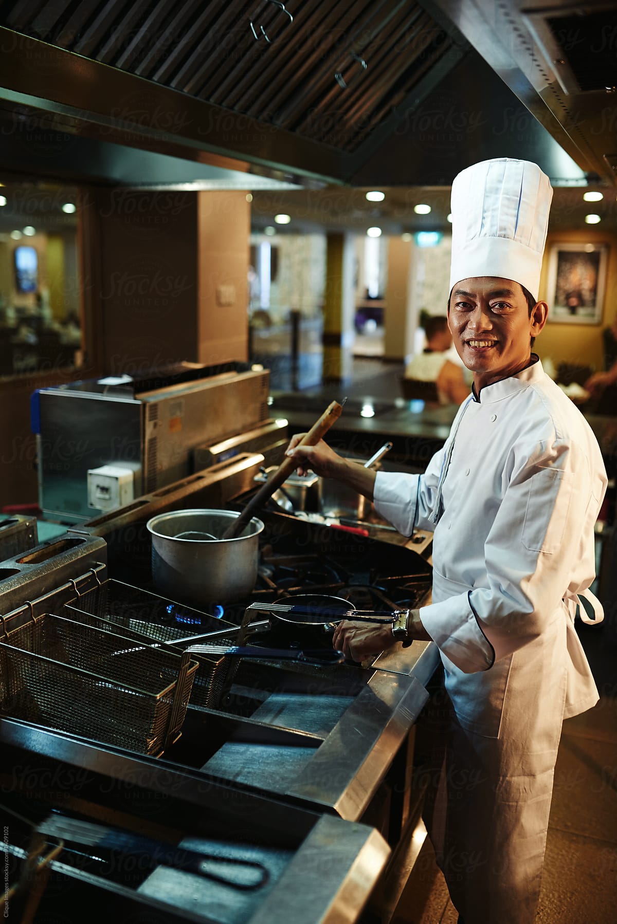 Young smiling chef cooking dish