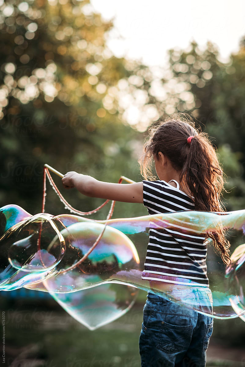 Girl playing with giant soap bubbles outdoors