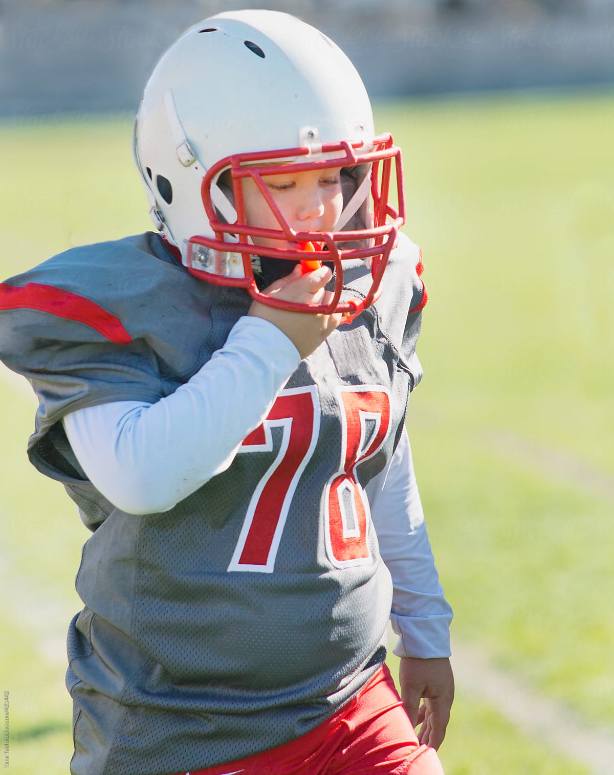 Young football player wearing helmet puts in his mouthpiece