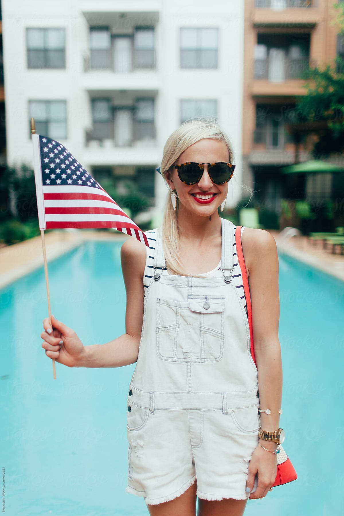 Young woman standing by a pool smiling with an American flag